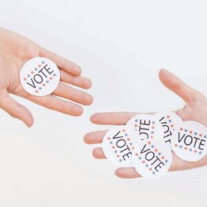 Close-up of hands holding election vote stickers, symbolizing participation.